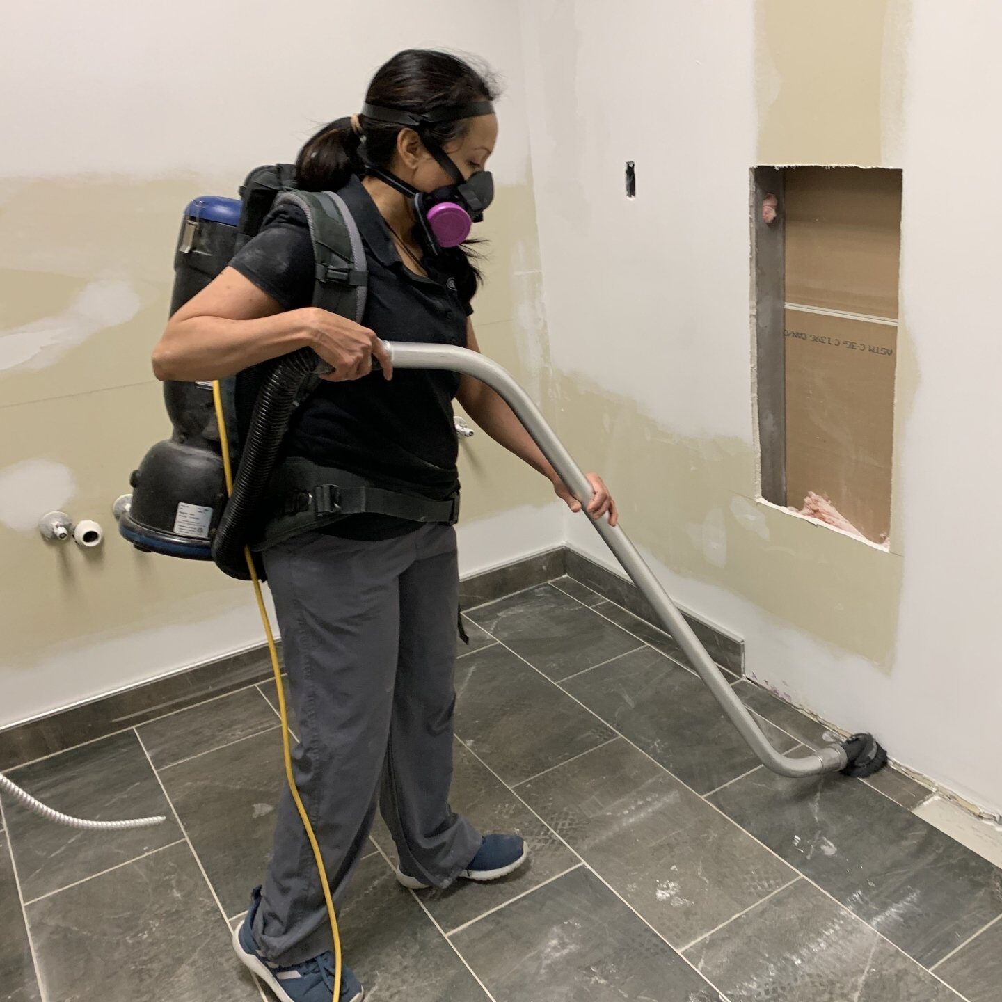 Woman wearing respirator vacuuming dust during renovations.